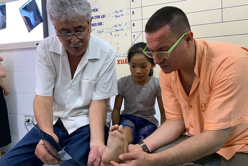 Angel Arnaud, MD, and Altug Tanriover, MD, with a patient in Vietnam